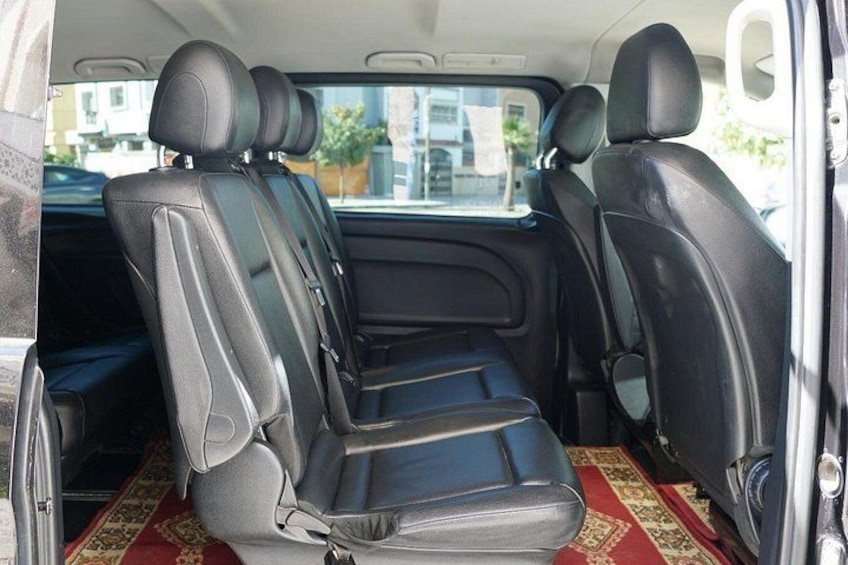 Interior de un coche con asientos de cuero negro y alfombra con estampado rojo. 4
