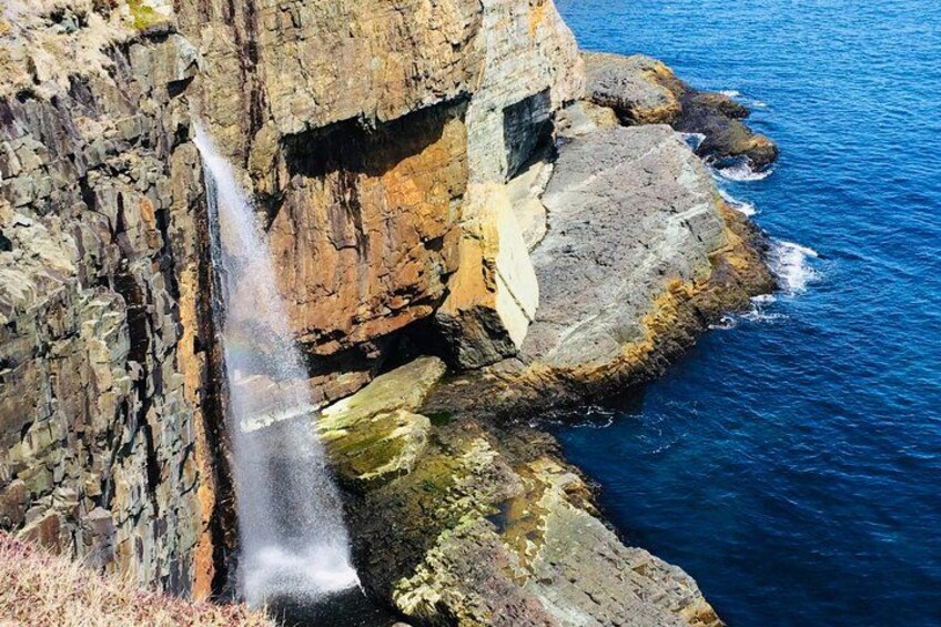 Une cascade se déversant en contrebas d’une falaise rocheuse dans l’océan. 1
