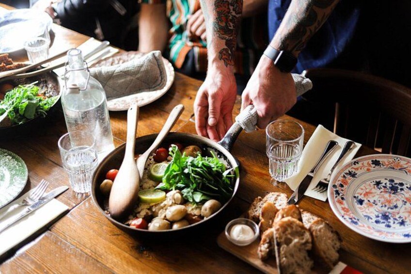 A wooden table with a bowl of salad, a bottle of water, and bread. 1
