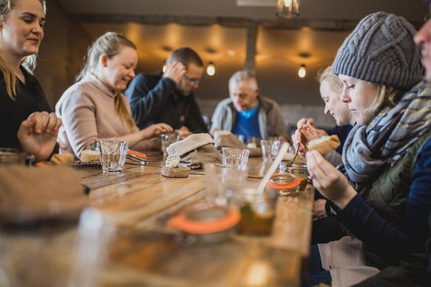 A group of people sitting around a wooden table, eating and drinking. 3