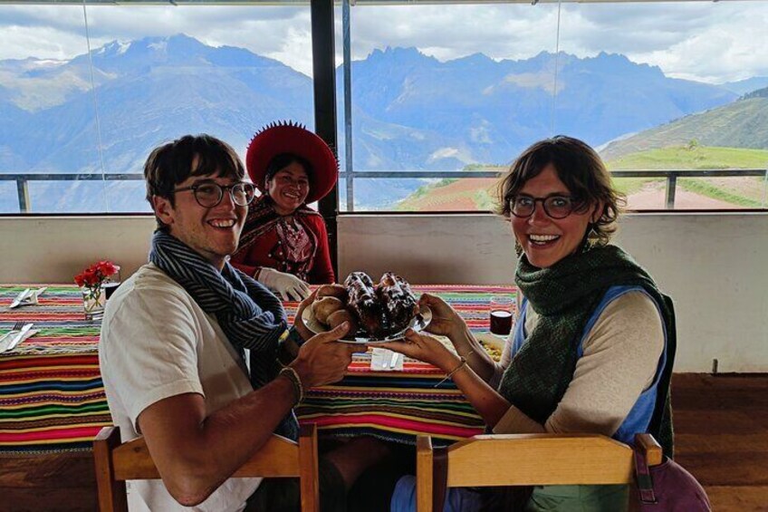 Three people sitting at a table with a view of mountains. 5