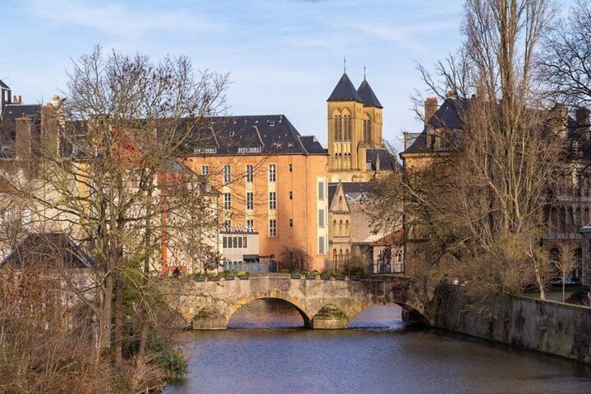Un puente de piedra sobre un río, edificios históricos y una torre. 2