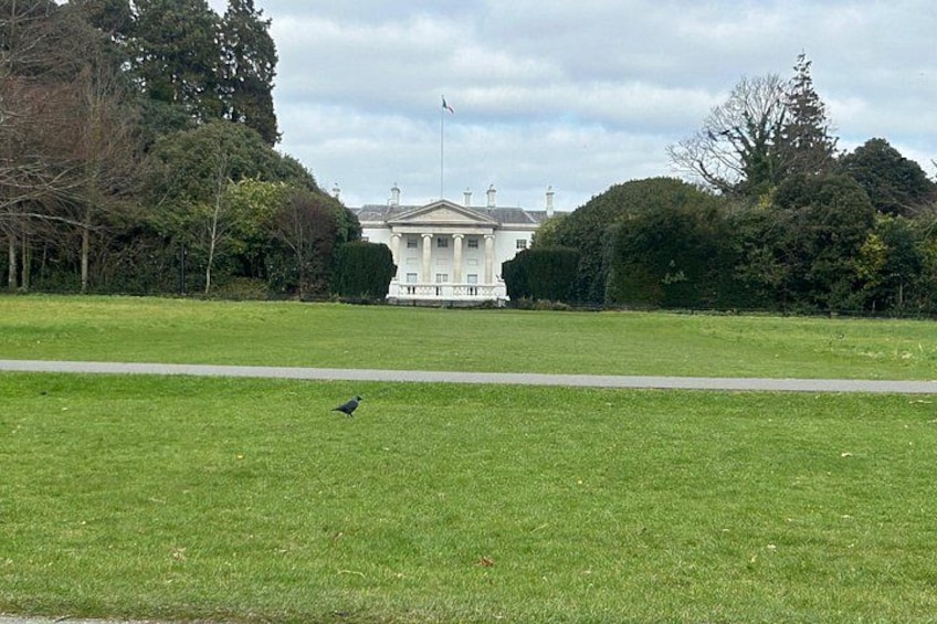 A grassy field with a bird, a white building with columns, and trees in the background. 5