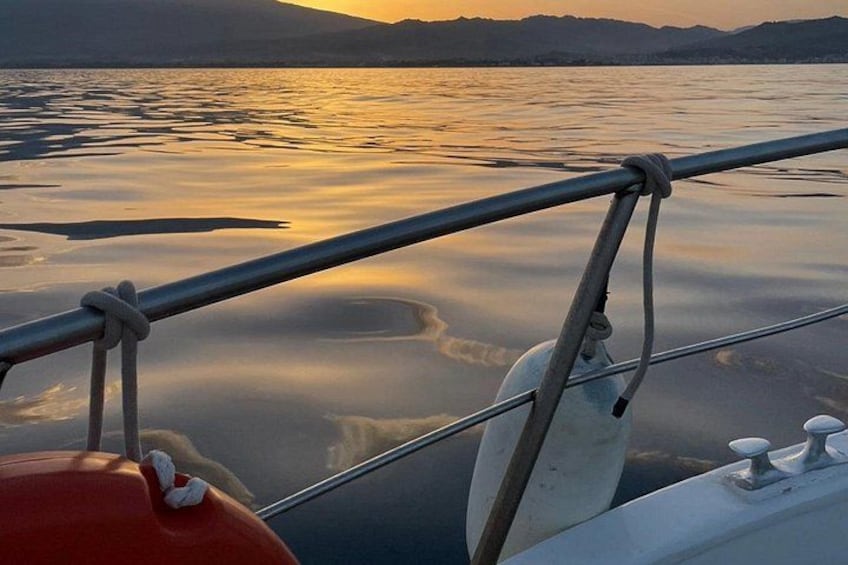 A calm lake at sunset with a boat's railing and a buoy. 2