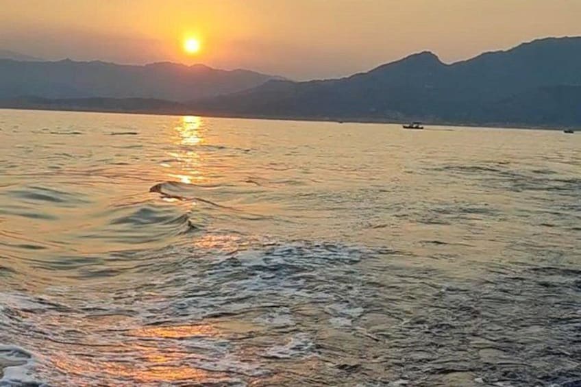 A sunset over a body of water with mountains in the background. 5