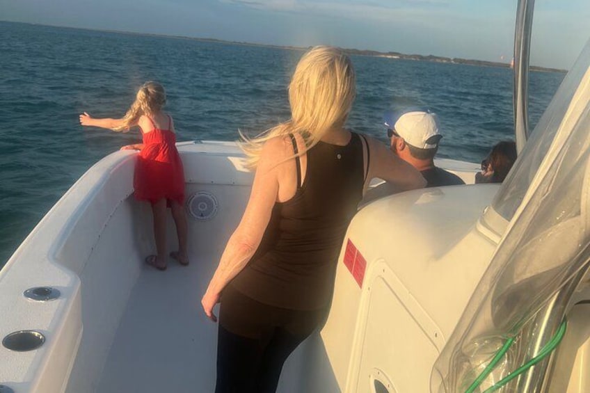 A boat with people on board, a child in a red dress, and a clear view of the water. 2