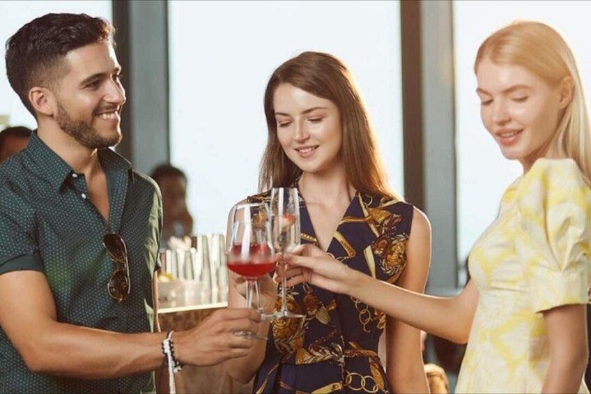 Una persona sosteniendo una copa de vino, otra persona con una botella, y una tercera persona de pie cerca. 2