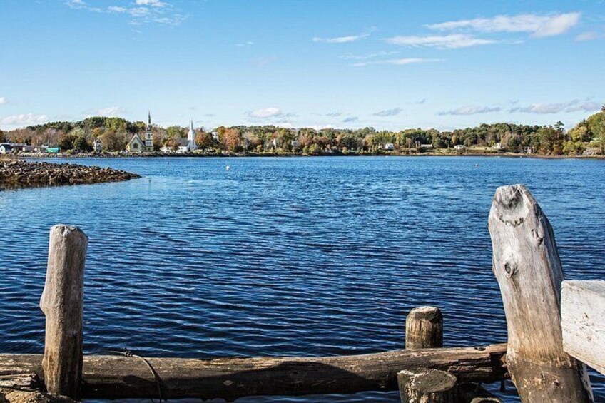 A calm lake with wooden posts in the foreground, a church on the opposite shore, and a forested hill in the background. 5