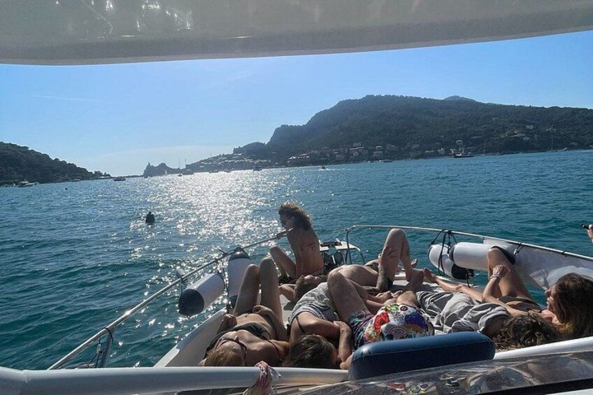 A boat with people lying on deck, water, and distant hills. 4