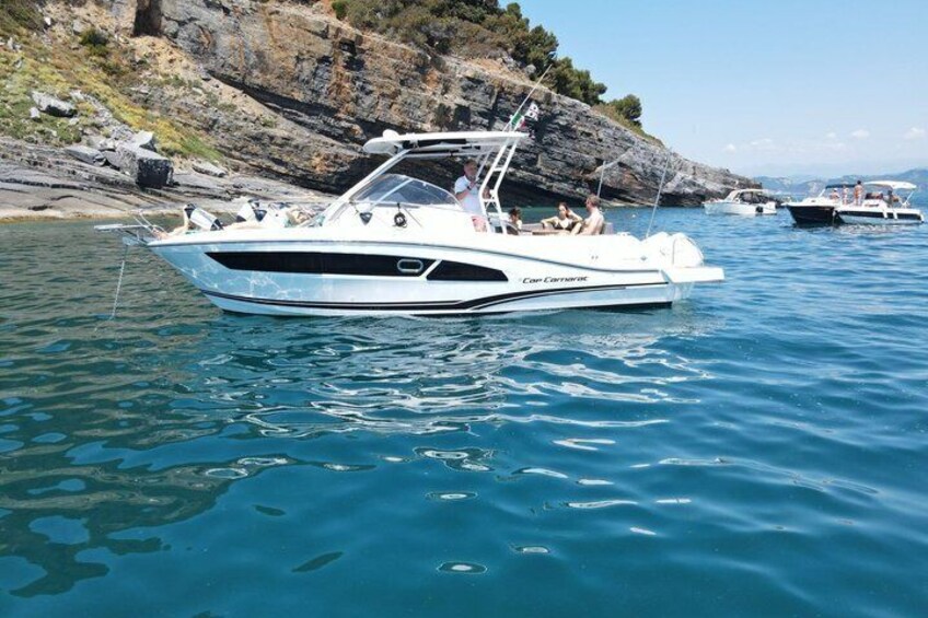 A white boat named 'Cor Corsaro' anchored near rocky cliffs. 1