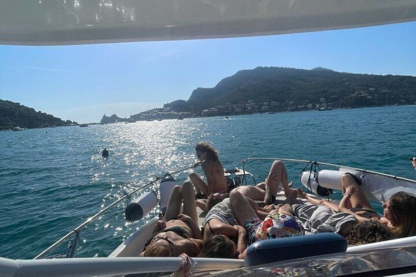 A boat with people reclining on deck, calm water, and distant hills. 4