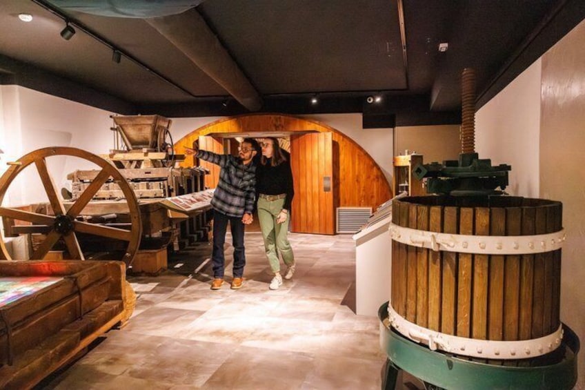 A museum interior with historical machinery, a wooden archway, and a large wooden barrel. 1