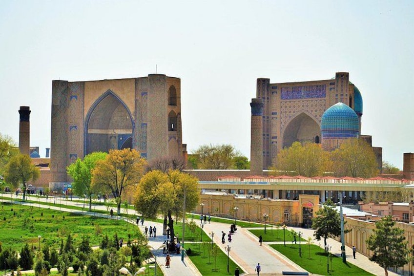 A large mosque with a dome and arched entrance, surrounded by a park with trees and a pathway. 2