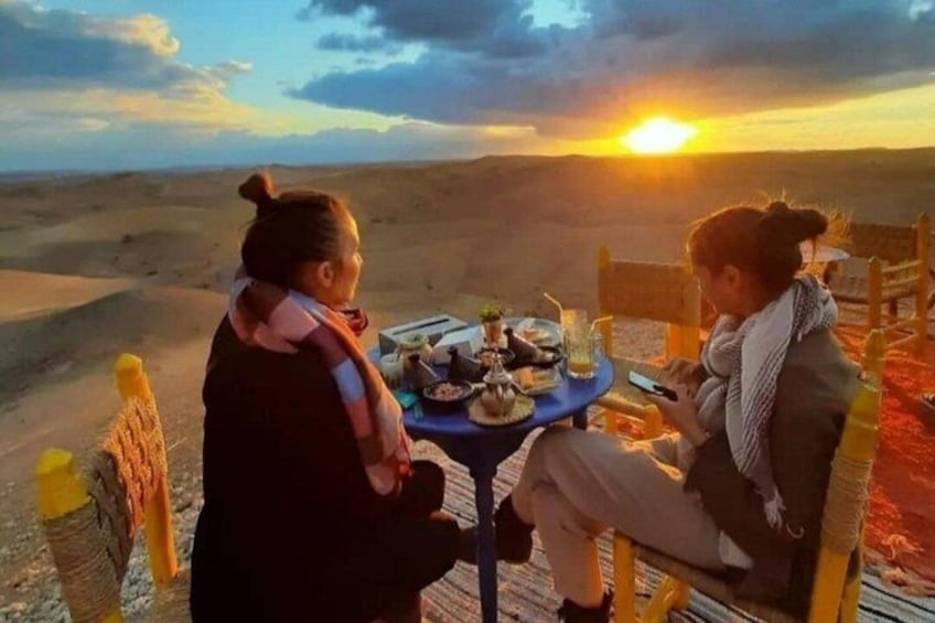 Two people sitting at a table with a sunset in the background. 1