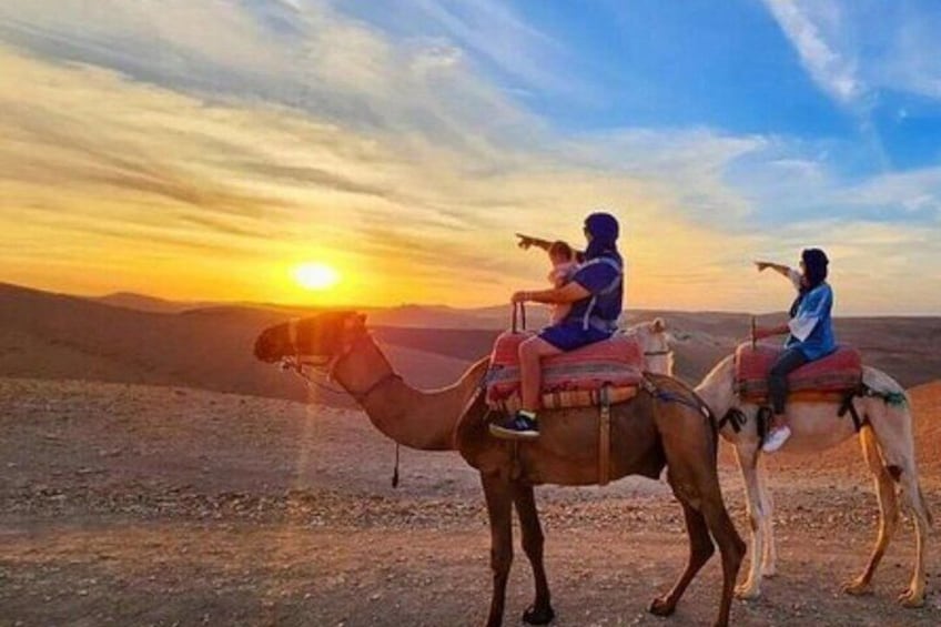Two camels with riders in a desert landscape at sunset. 2