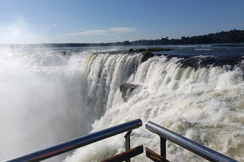 A large waterfall with a railing in the foreground. 4