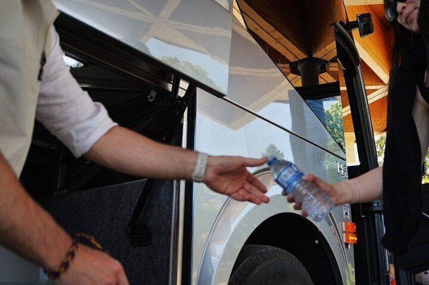 A person handing over a water bottle to another person near a vehicle. 3
