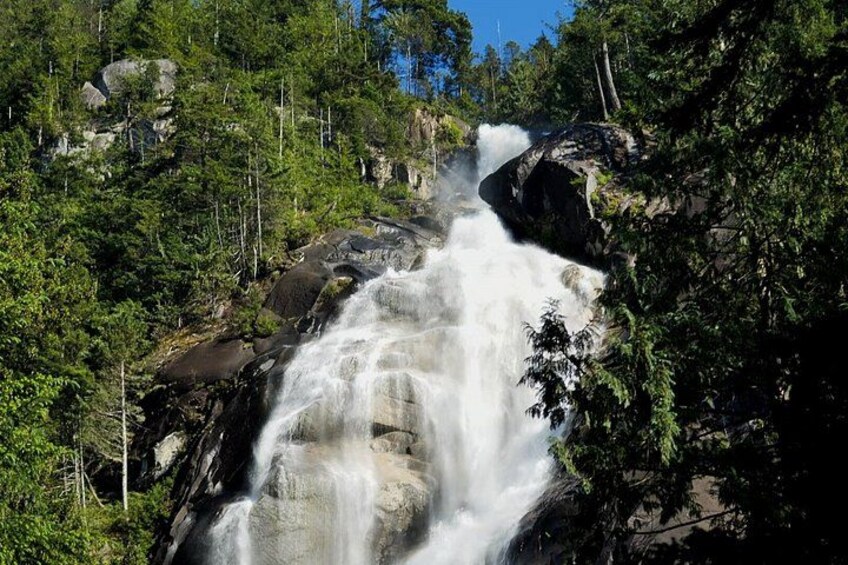 A waterfall cascading over rocks surrounded by dense forest. 2
