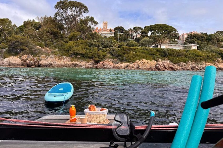 A boat with a blue paddleboard, a bottle, and a basket on the deck. 3
