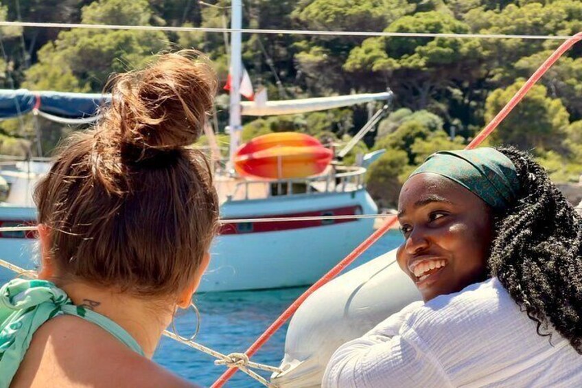 Two people on a boat with a lifebuoy and trees in the background. 2