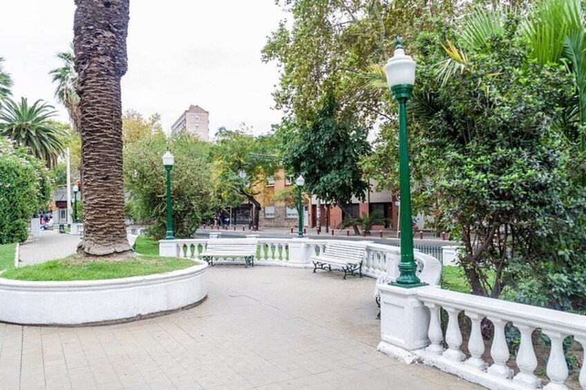 Un parc avec un palmier, des bancs et une clôture blanche. 2