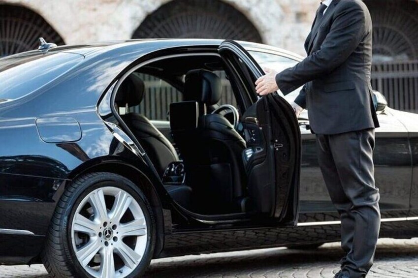 A man in a suit opening a car door. 1