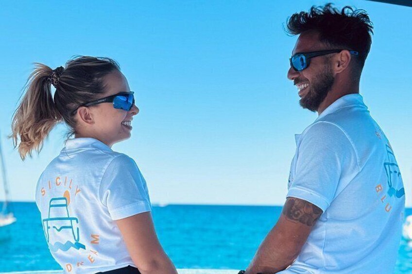 Two people on a boat with a clear blue sky and ocean in the background. 3