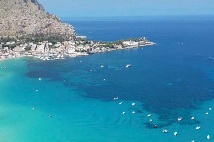 A coastal town with buildings along the shore, boats in the water, and a mountainous backdrop. 3