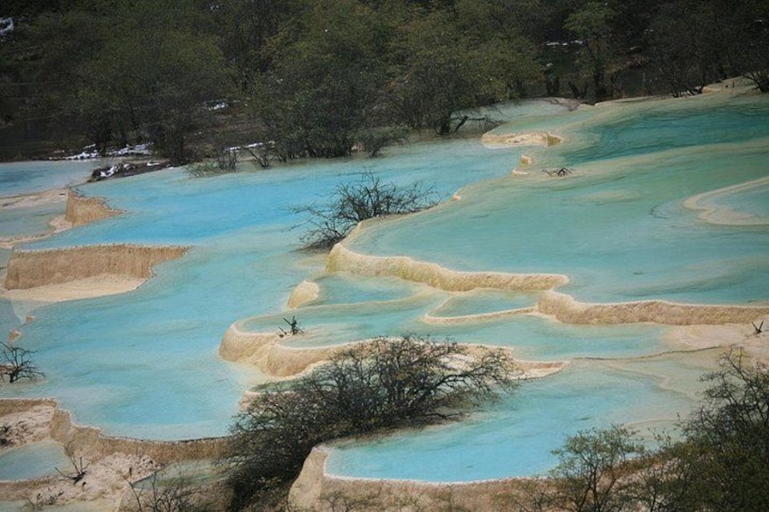 Des bassins en terrasses remplis d’eau turquoise, entourés d’une végétation clairsemée. 1