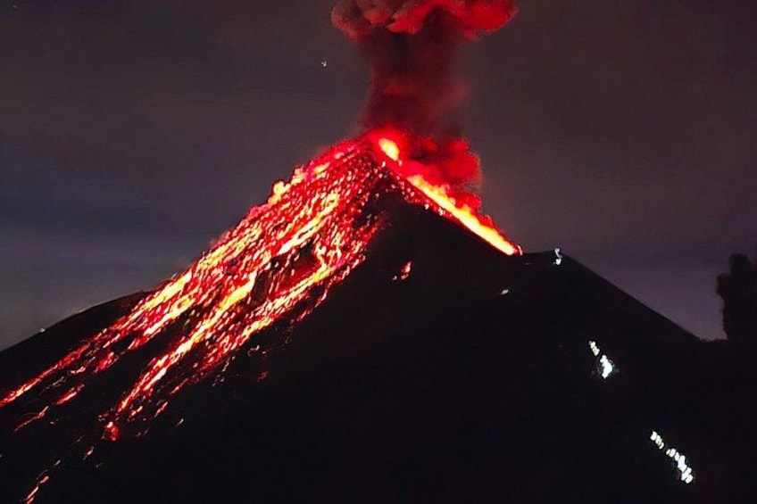 A volcano erupting at night with lava flowing down its side. 5