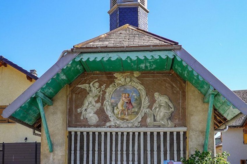 A building with a green roof, a mural with figures, and a chimney. 4