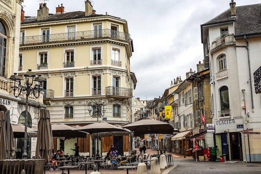 A street with outdoor cafes, a yellow sign, and a building with a sign that reads 'GLACIER'. 2