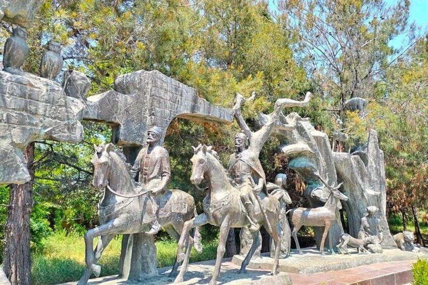 A stone sculpture of a man on horseback, a horse, and a tree with branches. 5