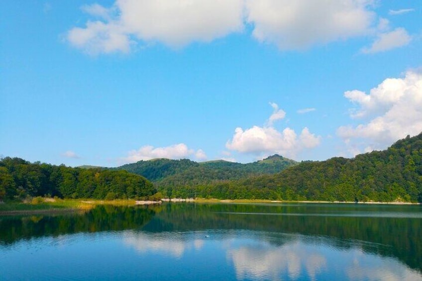 A calm lake with a forested mountain in the background. 2