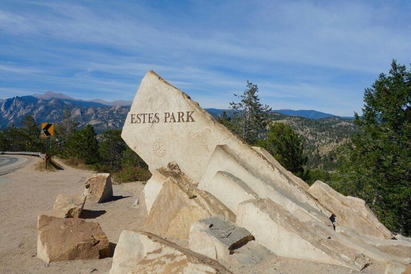 A large rock with 'ESTES PARK' carved on it, surrounded by smaller rocks and a mountainous landscape. 2