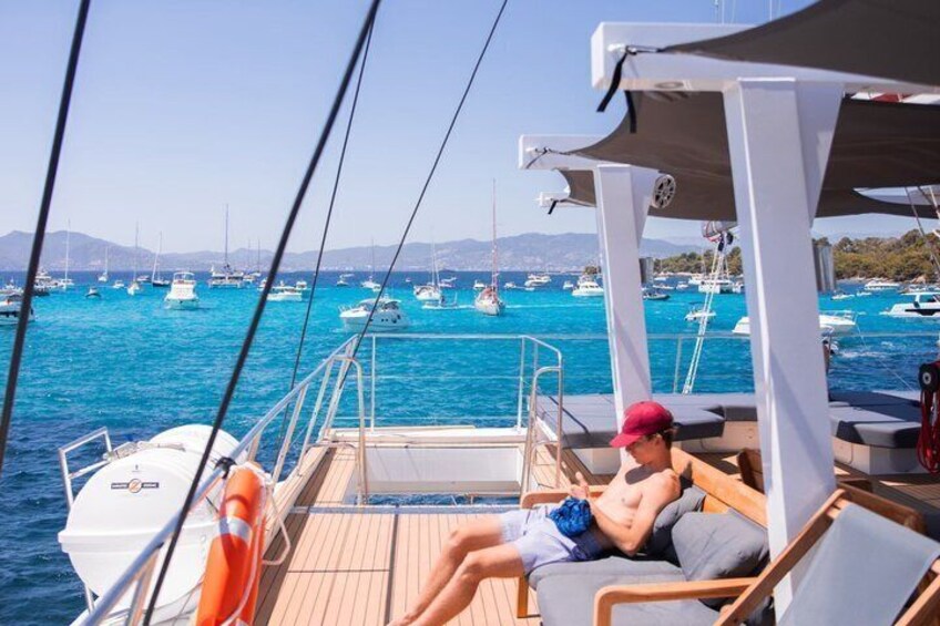 A person relaxing on a boat deck with a view of a marina filled with boats. 1