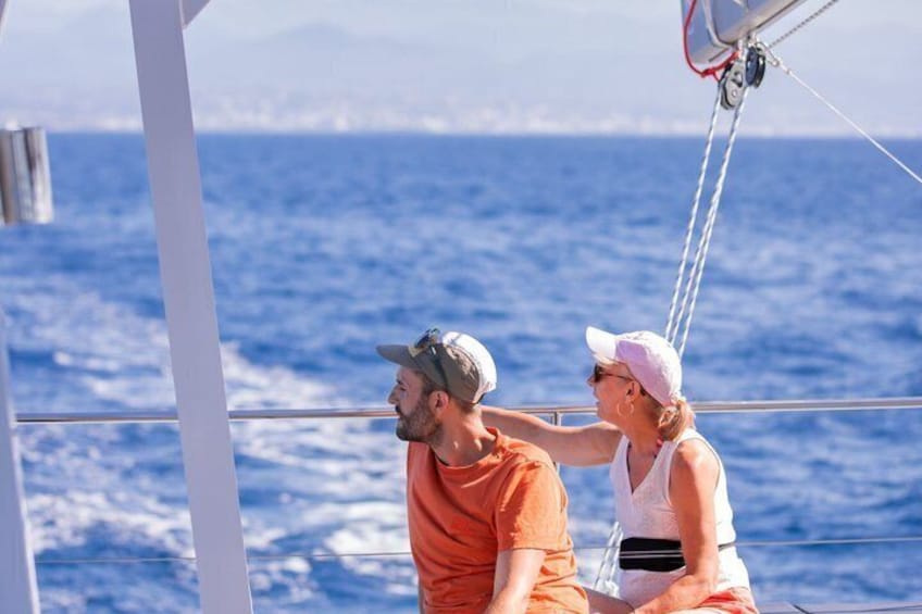 Two people on a sailboat with the ocean in the background. 1
