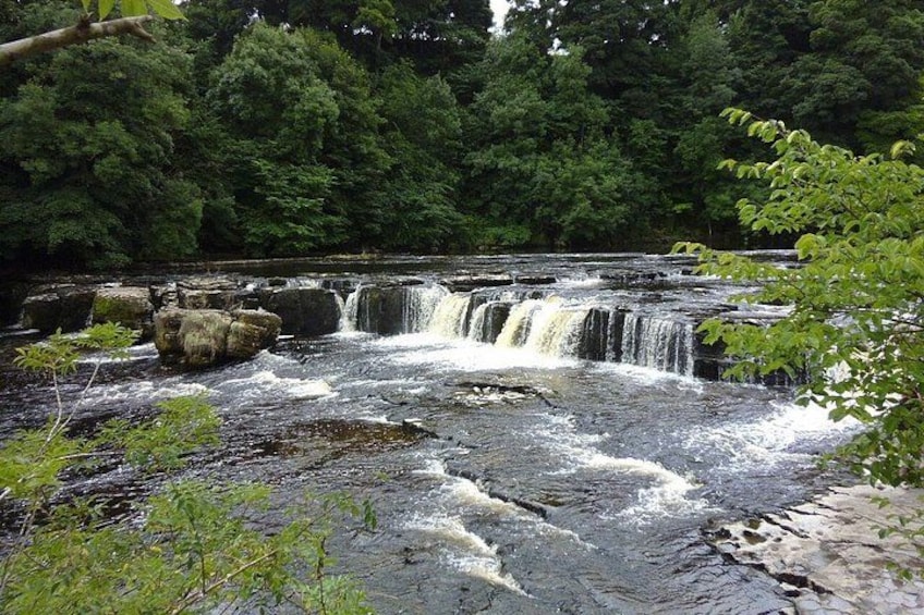A waterfall cascading over rocks in a forested area. 4
