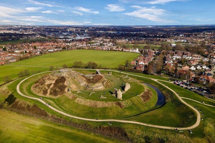 An aerial view of a historic site with a large mound, pathways, and a river. 3