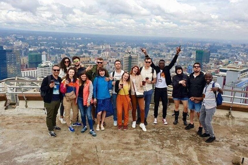 A group of people standing on a rooftop with a cityscape in the background. 1