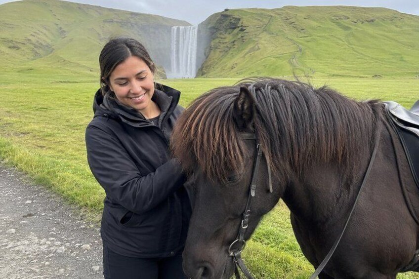 Une personne à cheval dans un champ verdoyant, avec une cascade en arrière-plan. 3