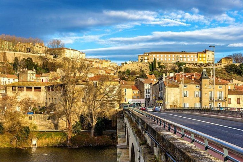 A river with a bridge, buildings on a hill, and a clear sky. 2