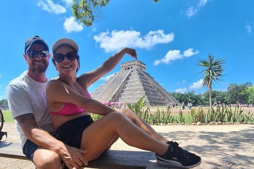 A couple sitting in front of a large pyramid structure. 3