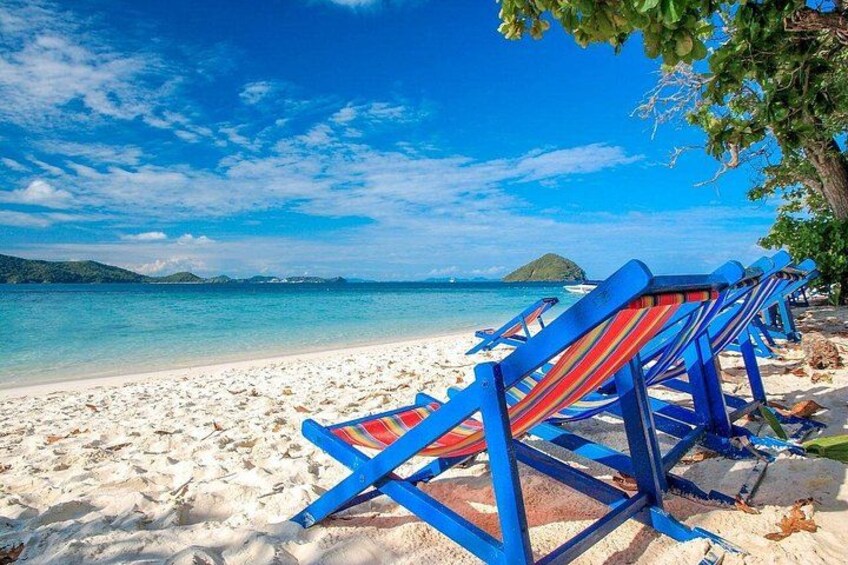 Una playa con sillas azules tipo lounge y un cielo azul despejado. 2