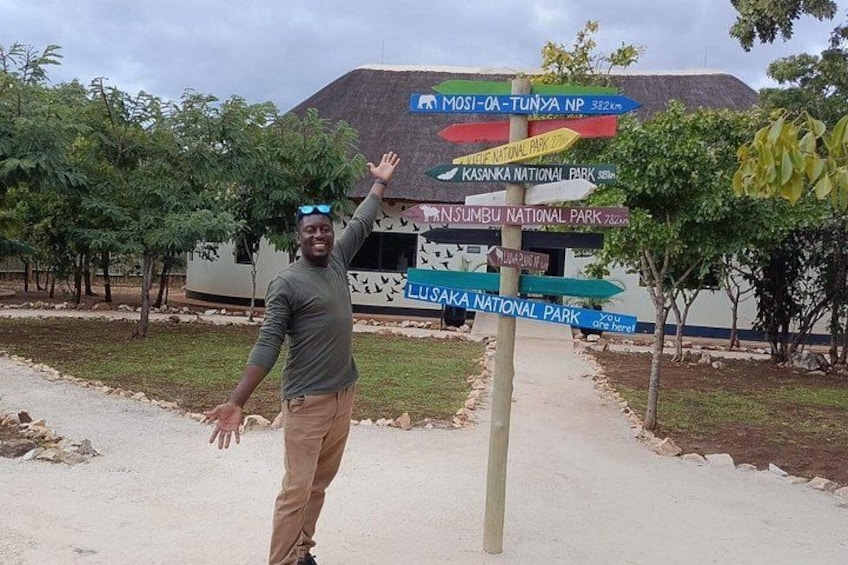 A person standing in front of a signpost with directions to various national parks. 2
