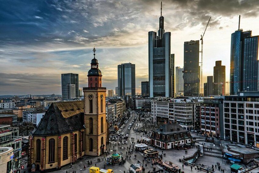 A cityscape with a historic church, modern skyscrapers, and a busy street. 5