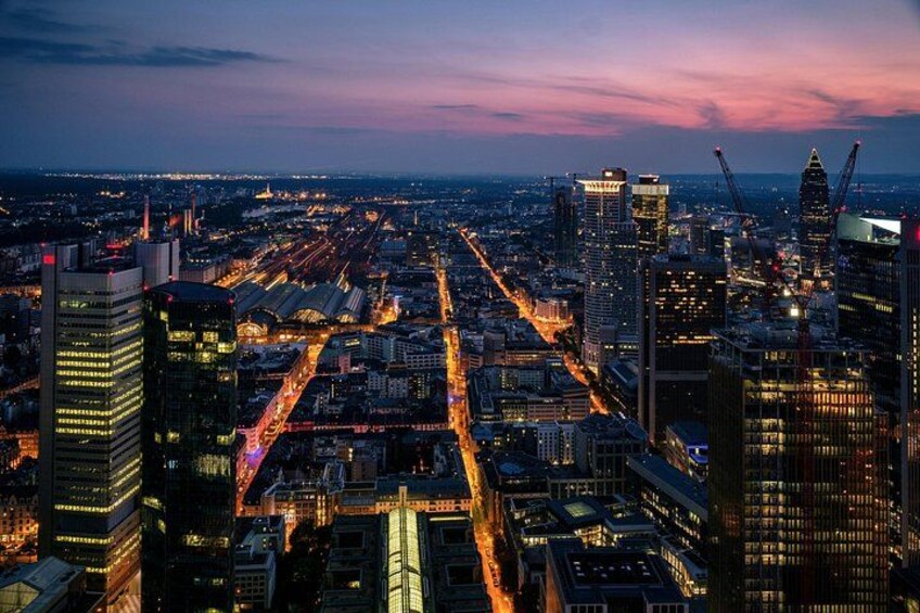 A cityscape at dusk with illuminated buildings and a network of roads. 2