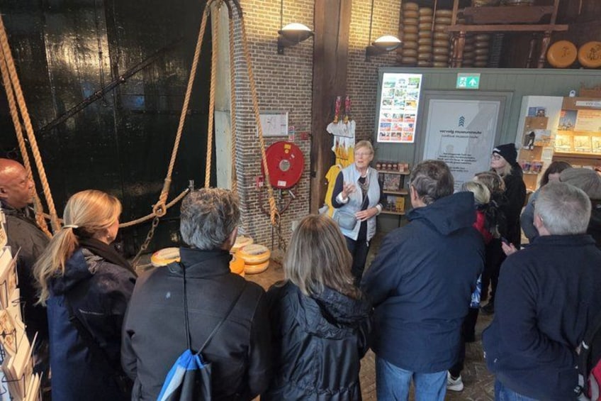 A group of people gathered around a speaker in a rustic setting with brick walls and wooden beams. 4