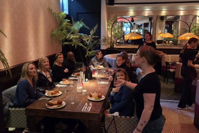 A group of people dining at a restaurant with wooden tables and potted plants. 2