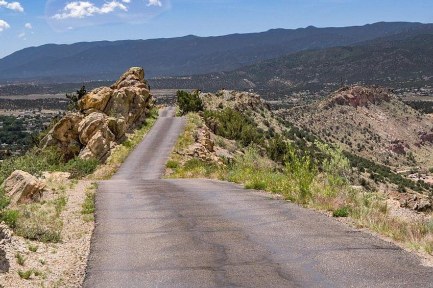 A paved road winding through a rocky landscape with distant mountains. 2